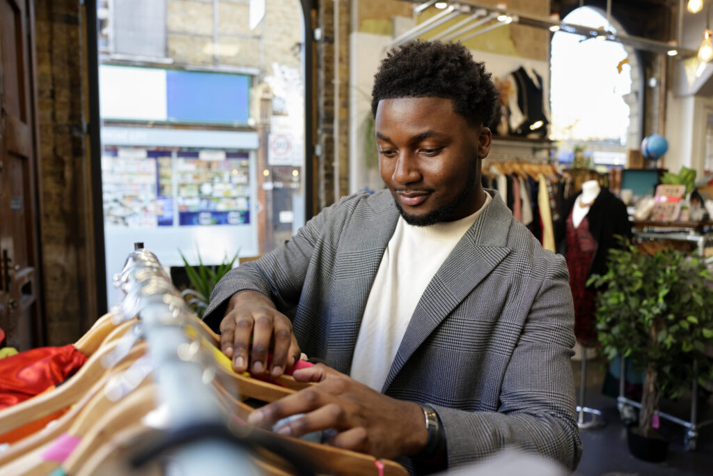 A man shopping for clothing in a vintage charity shop - sustainable fashion.